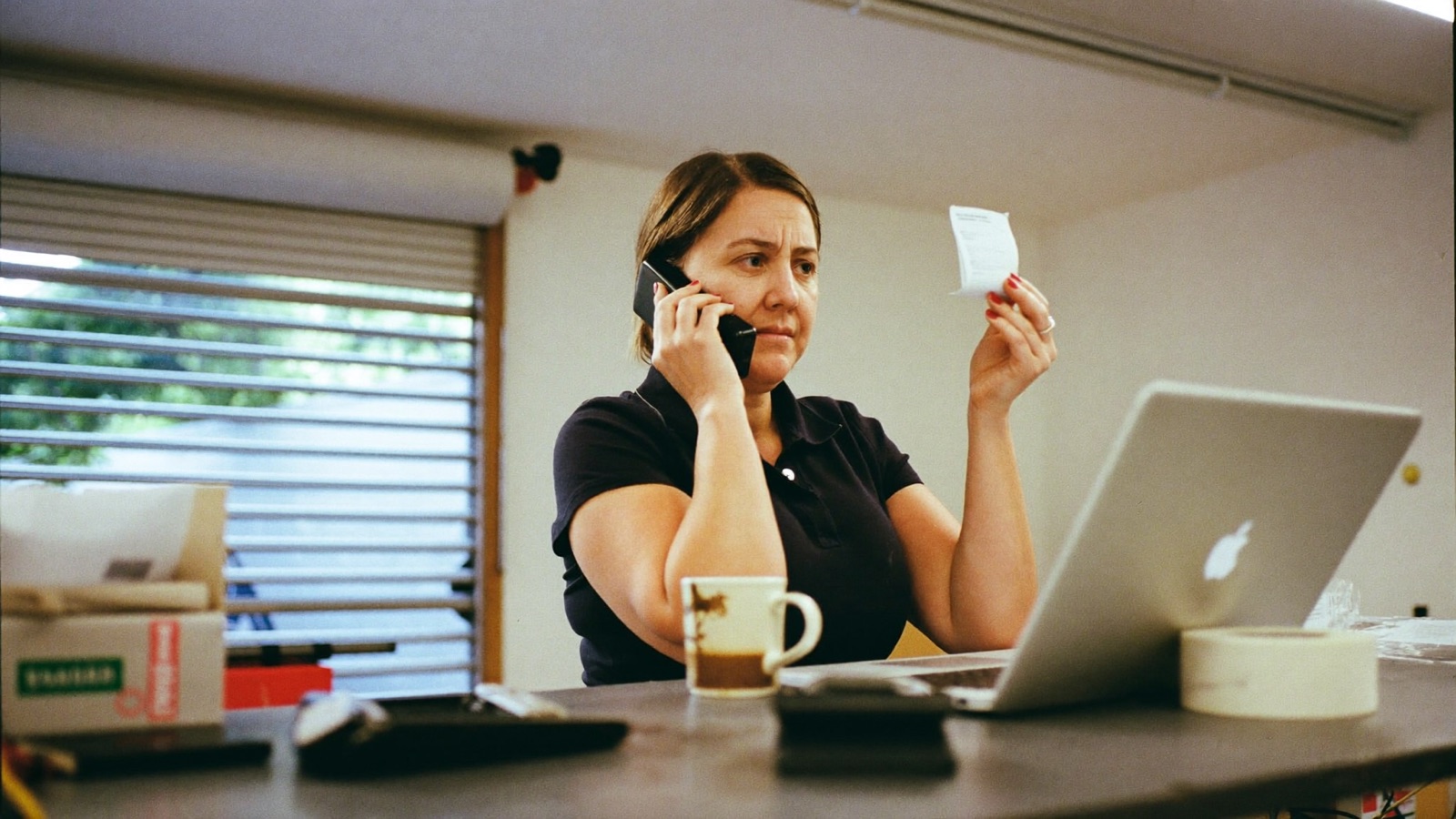 A local business owner comparing the Google Maps results on a phone with a laptop open beside it on a workbench